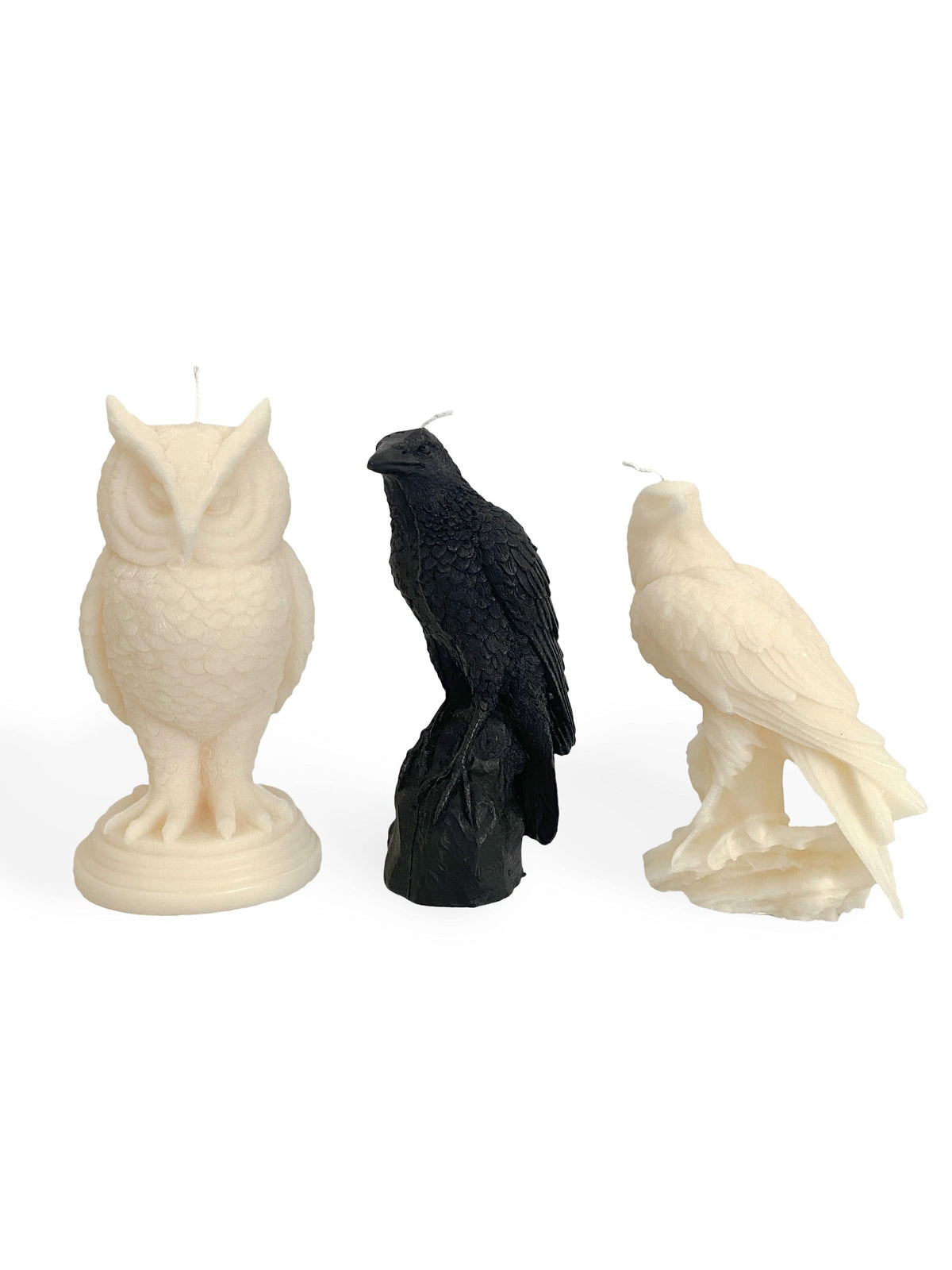 Three sculpted bird candles—A Pleasant Thought’s Snowy Owl Pillar Candle on the left, a black raven at center, and a hawk-like white bird on the right—stand upright against a white background. All are handcrafted in Canada from soy wax.