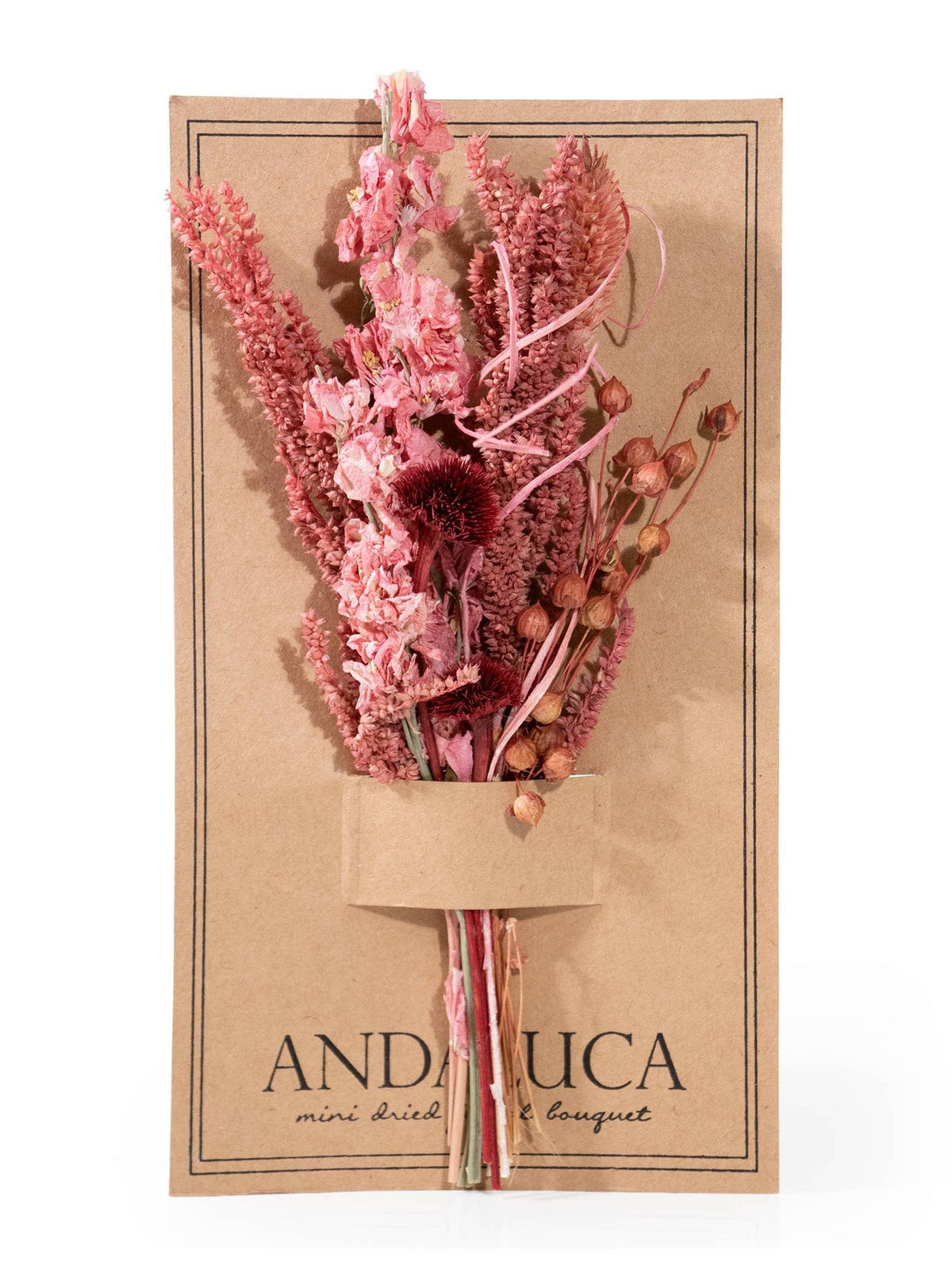 The Pink Wildflower Mini Bouquet by Andaluca features assorted pink dried flowers in a brown kraft paper holder, with a secure slot for the floral arrangement—a charming decorative accent.