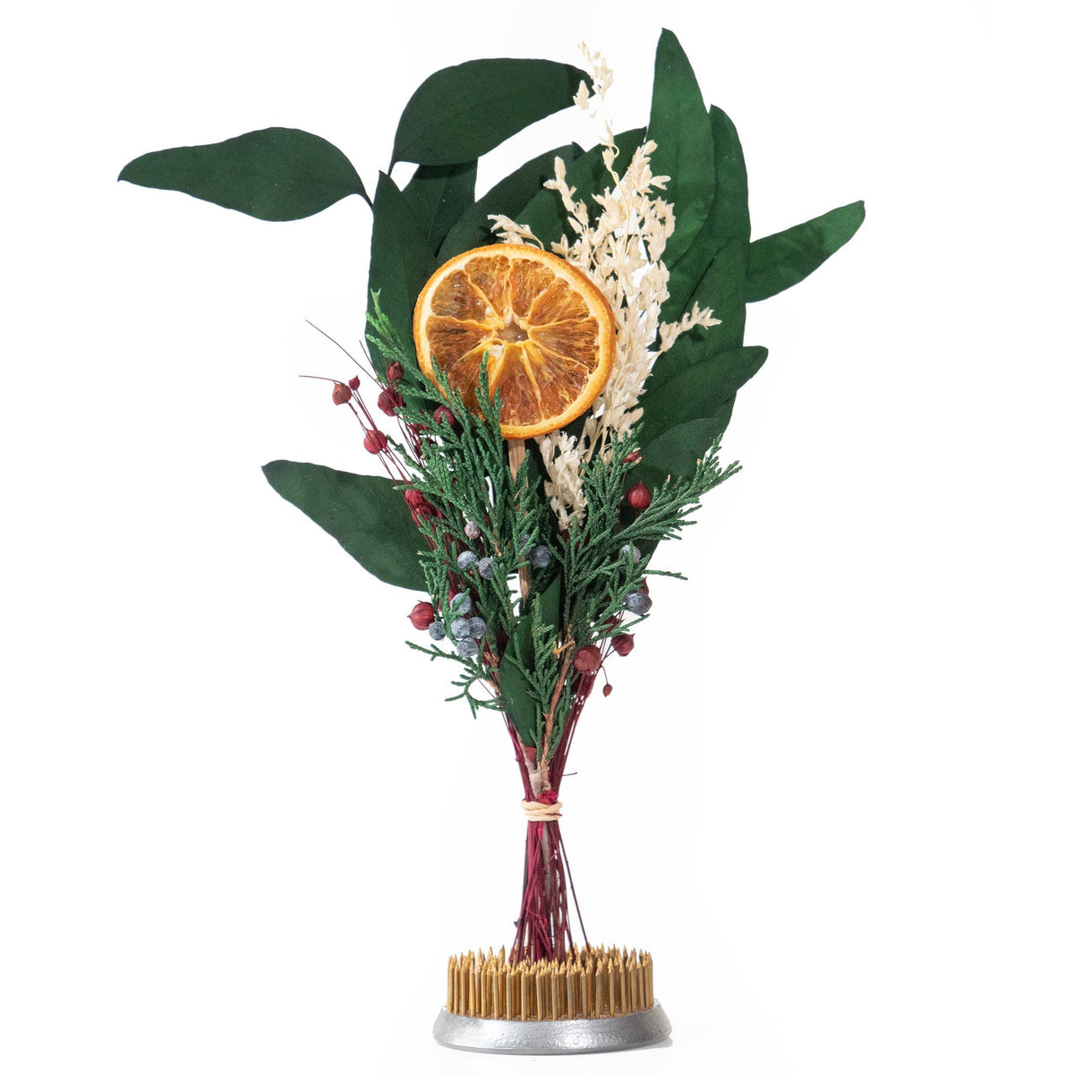 The Andaluca Winter Citrus Mini Bouquet features green leaves, red berries, white dried flowers, and a natural orange slice tied with red string in a metal base—an ideal accent for any space.