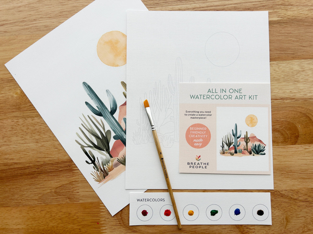 The Breathe People Desert Cactus All-In-One Beginner Watercolor Kit includes a brush, 5-color palette, pre-outlined canvas, instruction card, and a finished cacti and sun painting—perfect to start your watercolor journey.