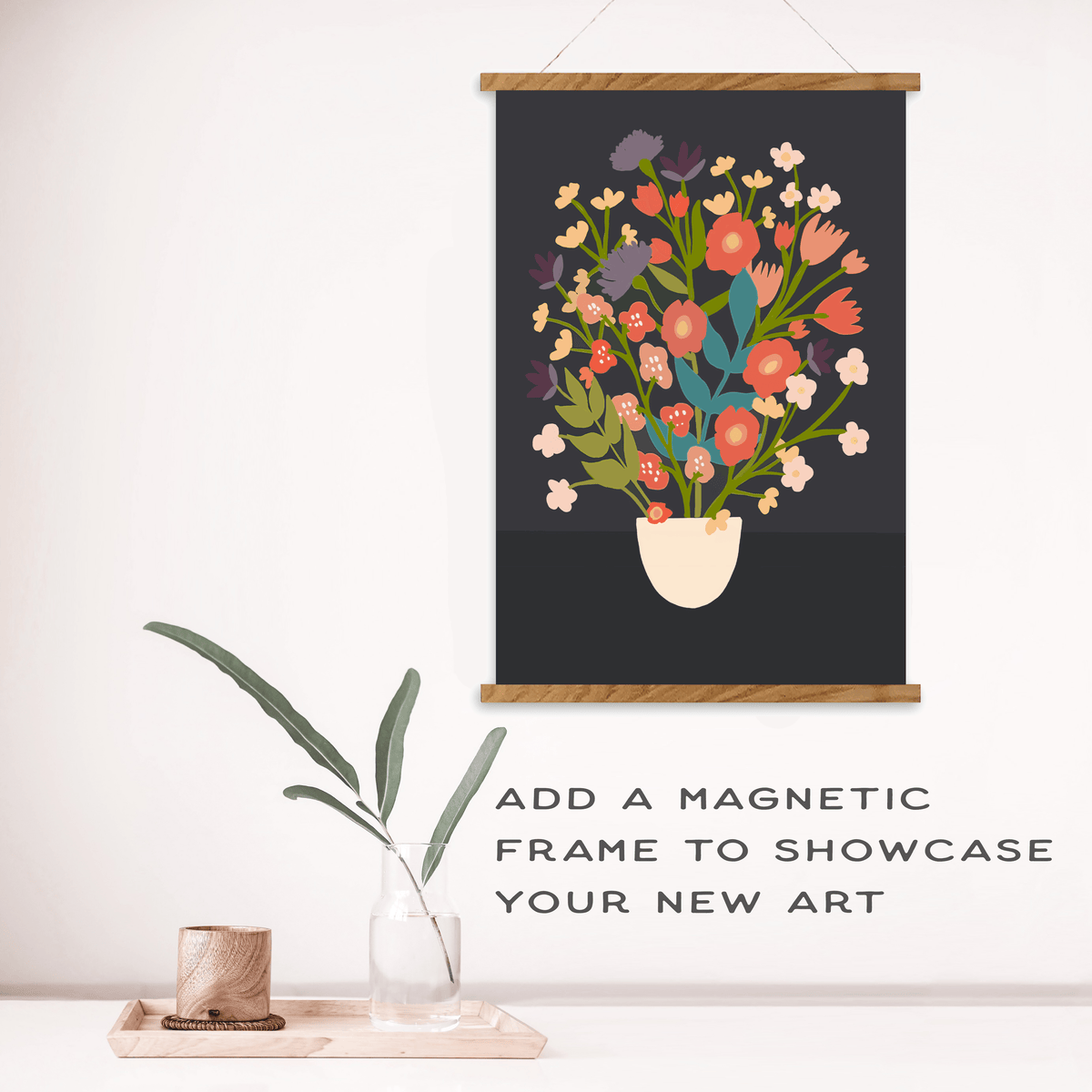 A vibrant floral print inspired by the Flower Bouquet Paint by Number Kit from Breathe People, displayed in a magnetic wooden frame, hangs on a white wall above a table with a glass vase. Text: “Add a magnetic frame to showcase your new art.”.