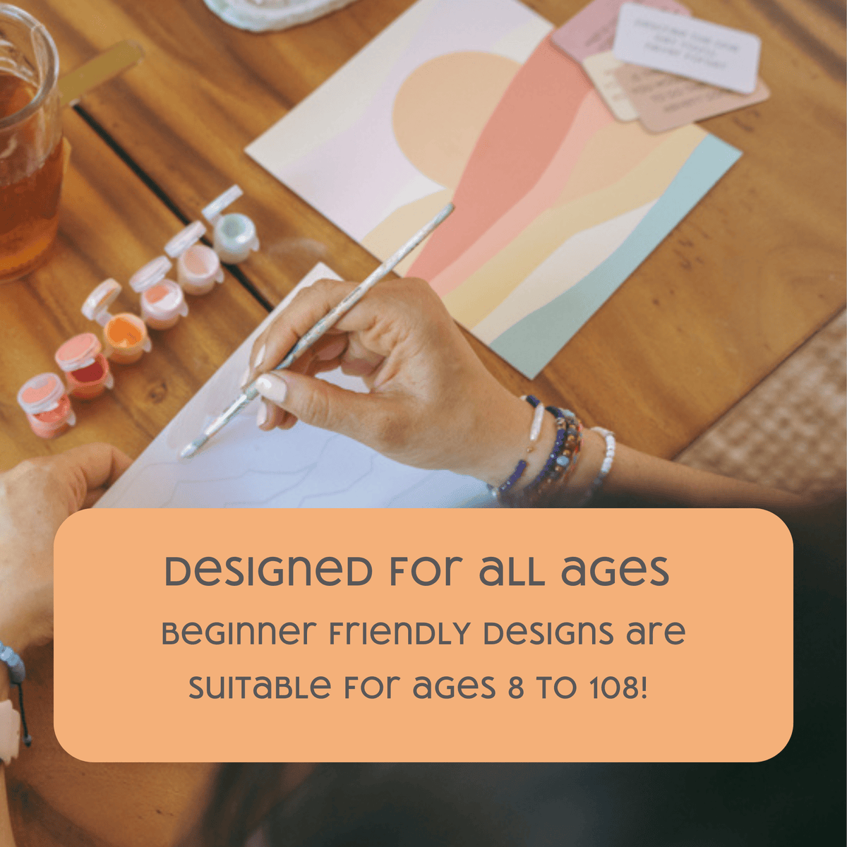 A person painting at a table with the Night Butterfly Garden Paint by Number Kit by Breathe People. Text overlay: Beginner-friendly designs for ages 8 to 108—creativity for all!.