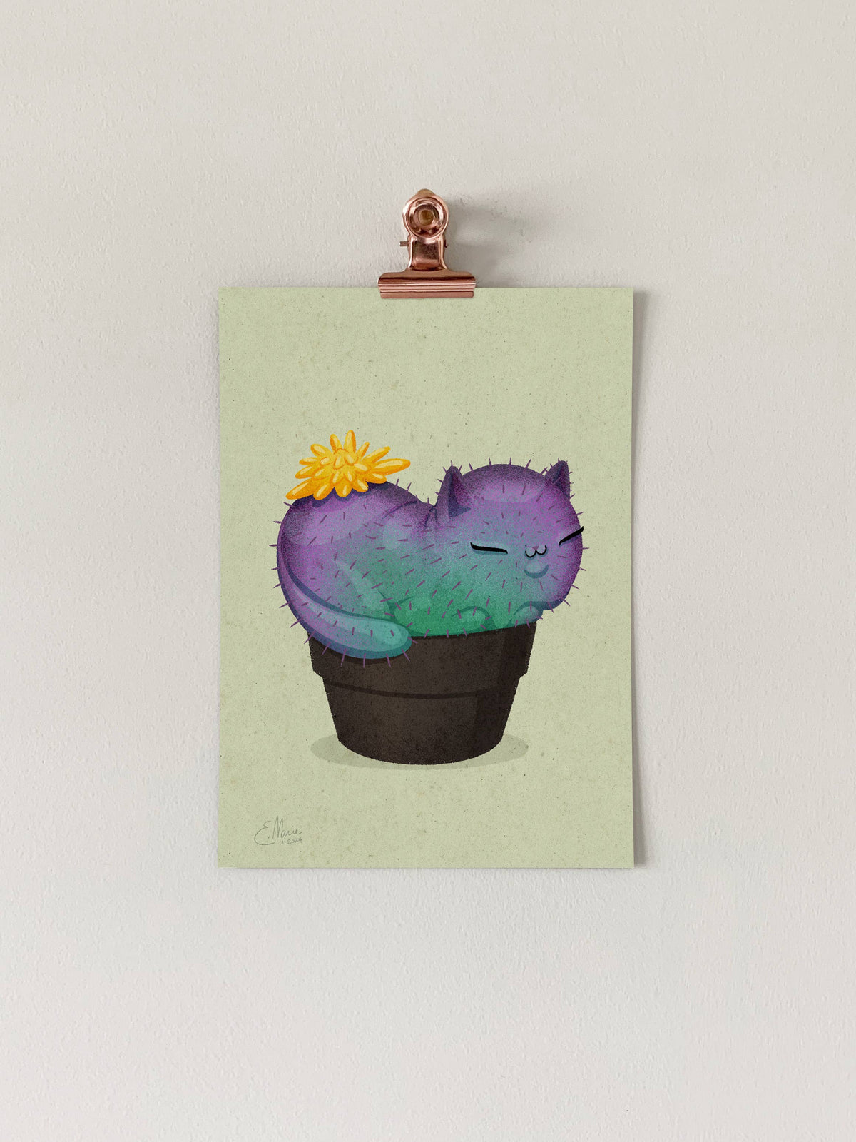 The Yellow Prickly Purr Catcus 7 x 5 art print by Elissa Marie Creative shows a cactus shaped like a sleeping cat with green and purple hues, a yellow flower on its back, in a black pot against a light wall.
