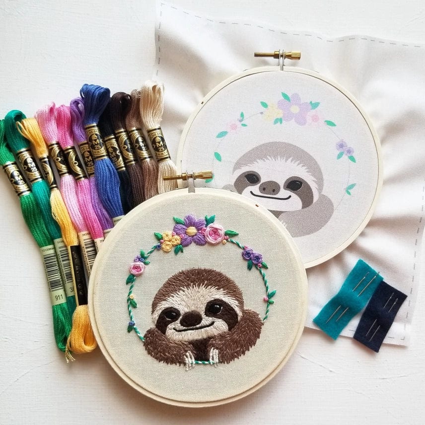 The 5 Beginner Smiling Sloth Embroidery Kit by Jessica Long Embroidery includes a finished colorful sloth hoop and a printed pattern, plus floss and needles—perfect for charming DIY handmade gifts.