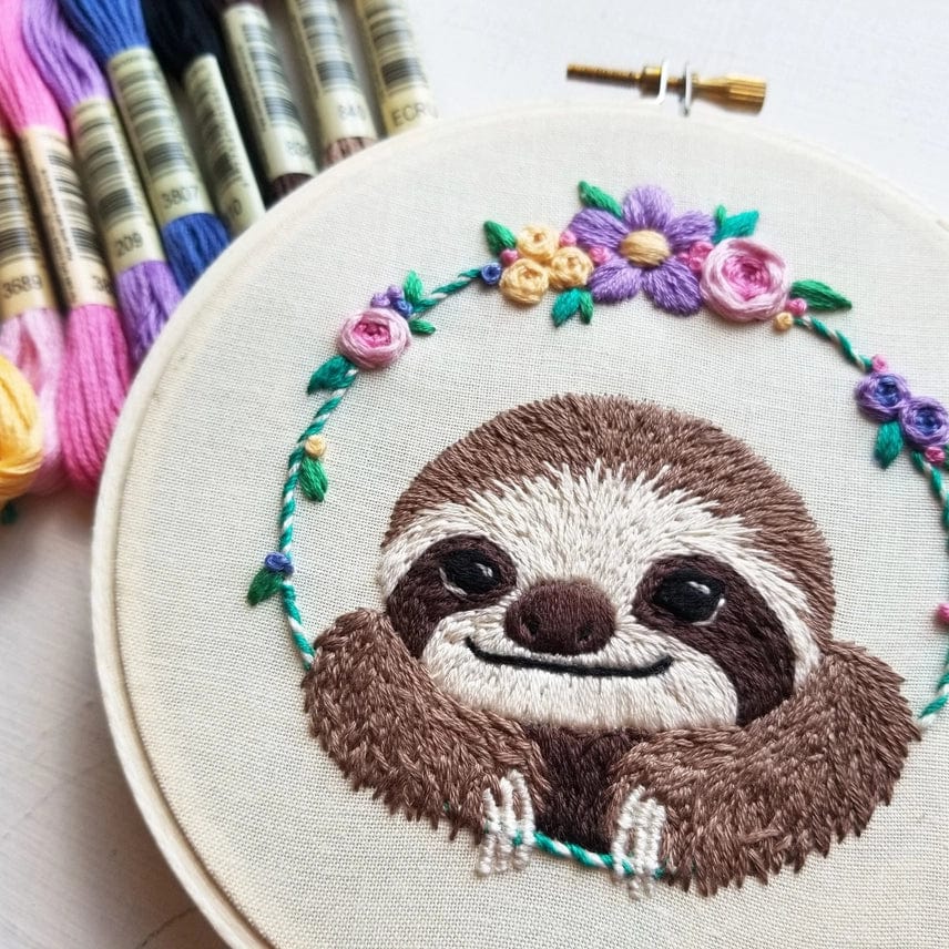 The 5 Beginner Smiling Sloth Embroidery Kit by Jessica Long Embroidery features a cheerful sloth with vibrant floral accents, colorful floss, and charming hoop art—perfect for DIY gift making or creative beginners.