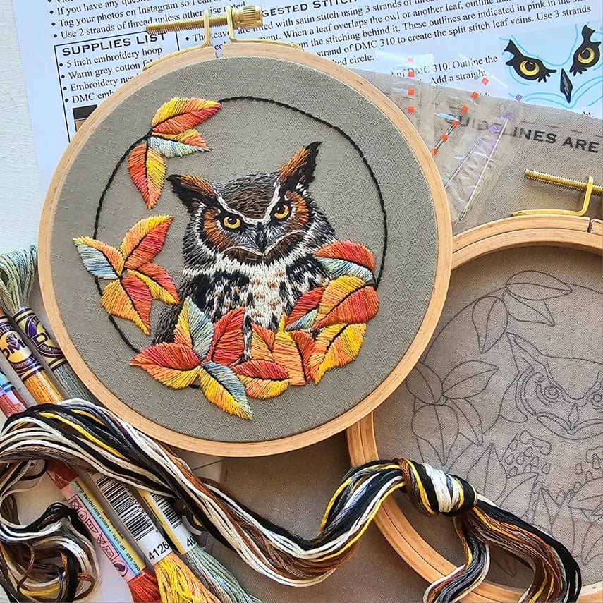The *Late May Pre-Order* 5 Great Horned Owl Embroidery Kit by Jessica Long Embroidery features a hoop with a detailed owl among autumn leaves, with threads, needle, and an unfinished outlined hoop on a craft table.