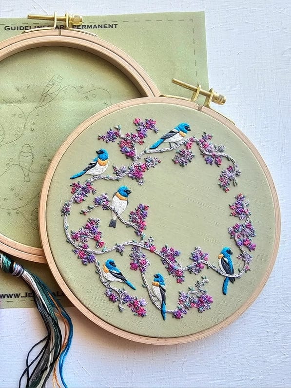 The *Late May Pre-Order* 6 Birds & Blooms Embroidery Kit by Jessica Long Embroidery features blue and yellow birds on pink-blossomed branches—ideal for beginners. The kit includes a hoop, embroidery pattern, and threads.