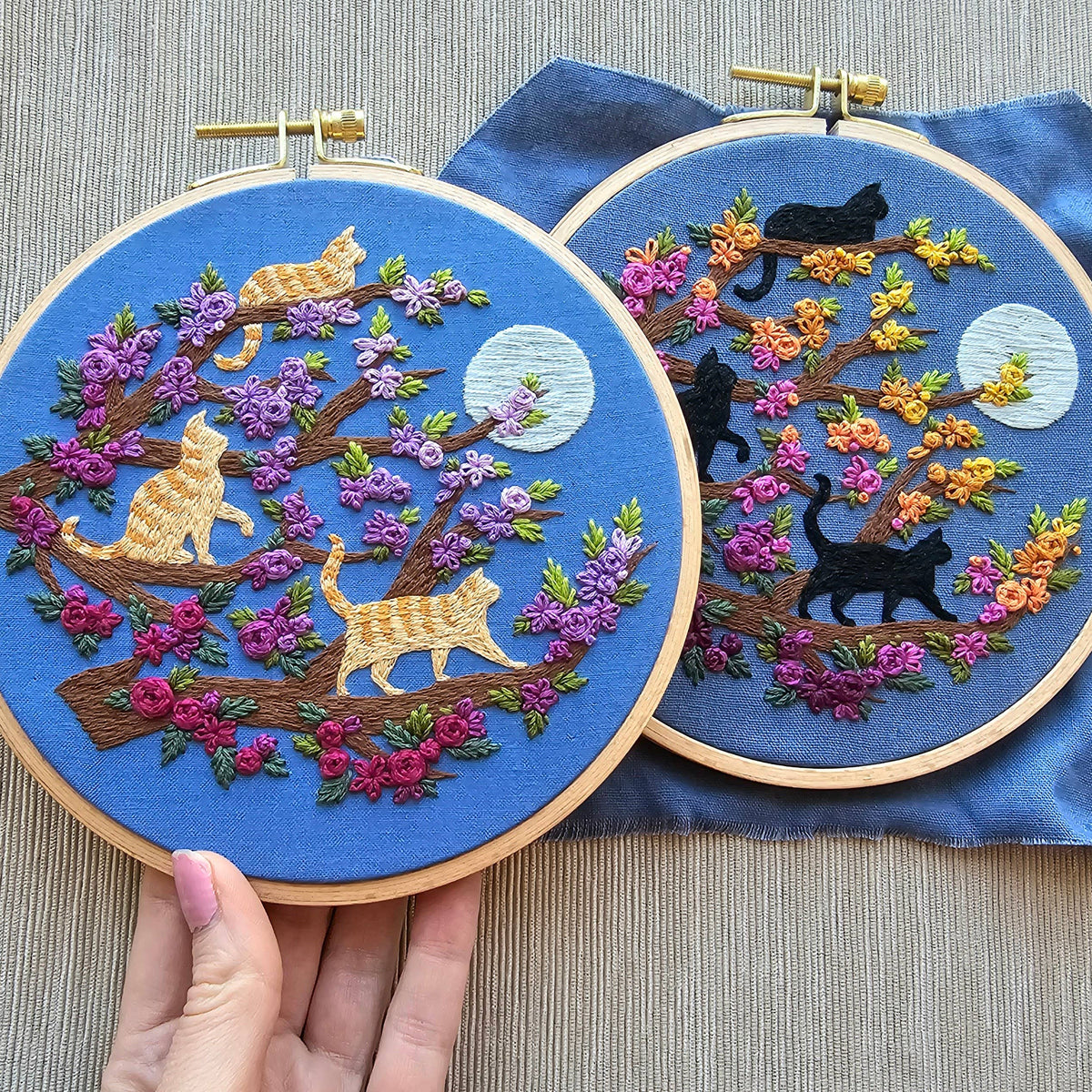 The 6 Beginner Orange Cats & Full Moon Embroidery Kit by Jessica Long Embroidery features colorful floral trees with orange and tan cats under a full moon, plus beginner-friendly instructions for your next charming hoop art.
