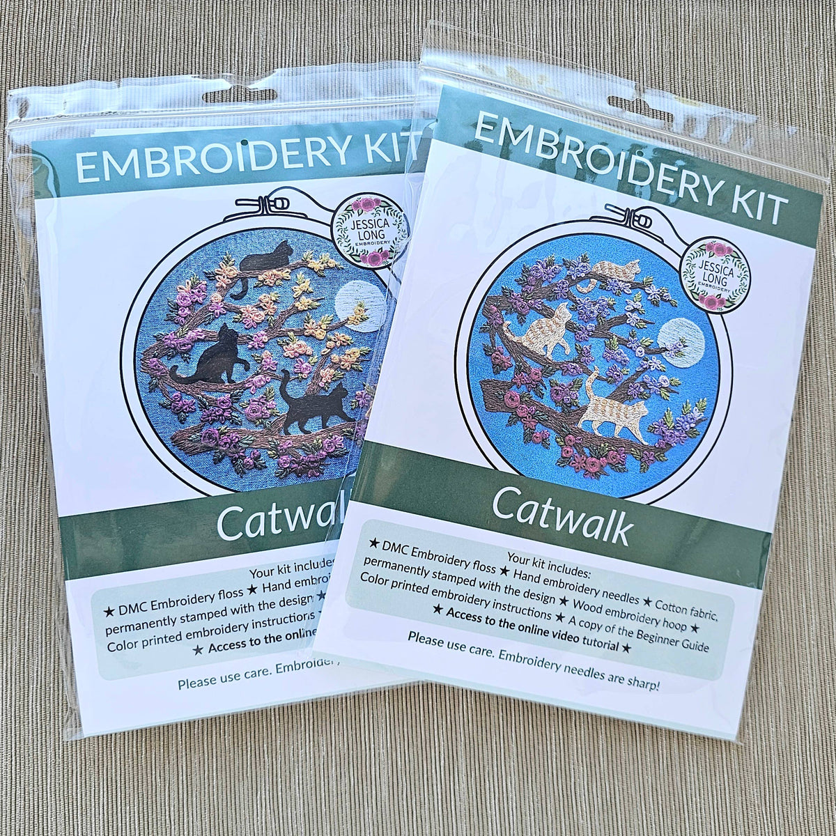 Two packaged 6 Beginner Orange Cats & Full Moon Embroidery Kits by Jessica Long Embroidery, each featuring circular hoop art with cats, flowers, and trees on a blue background. Includes beginner-friendly instructions for all skill levels.