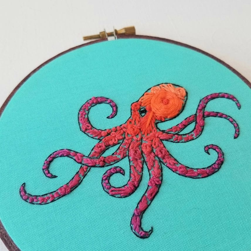 The 5 Beginner Pacific Octopus Embroidery Kit by Jessica Long Embroidery features a vibrant orange and pink octopus on turquoise fabric—detailed tentacles make it perfect ocean wall art for any sea life lover.