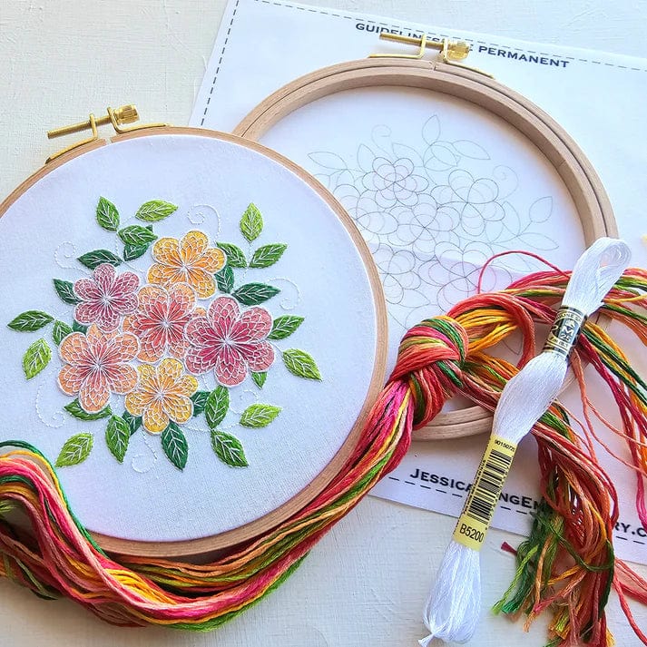 The 6 Lacy Flowers Embroidery Kit by Jessica Long Embroidery includes a hoop with colorful thread-painted flowers and leaves, a floral outline hoop, multicolored embroidery floss, and a printed paper pattern.