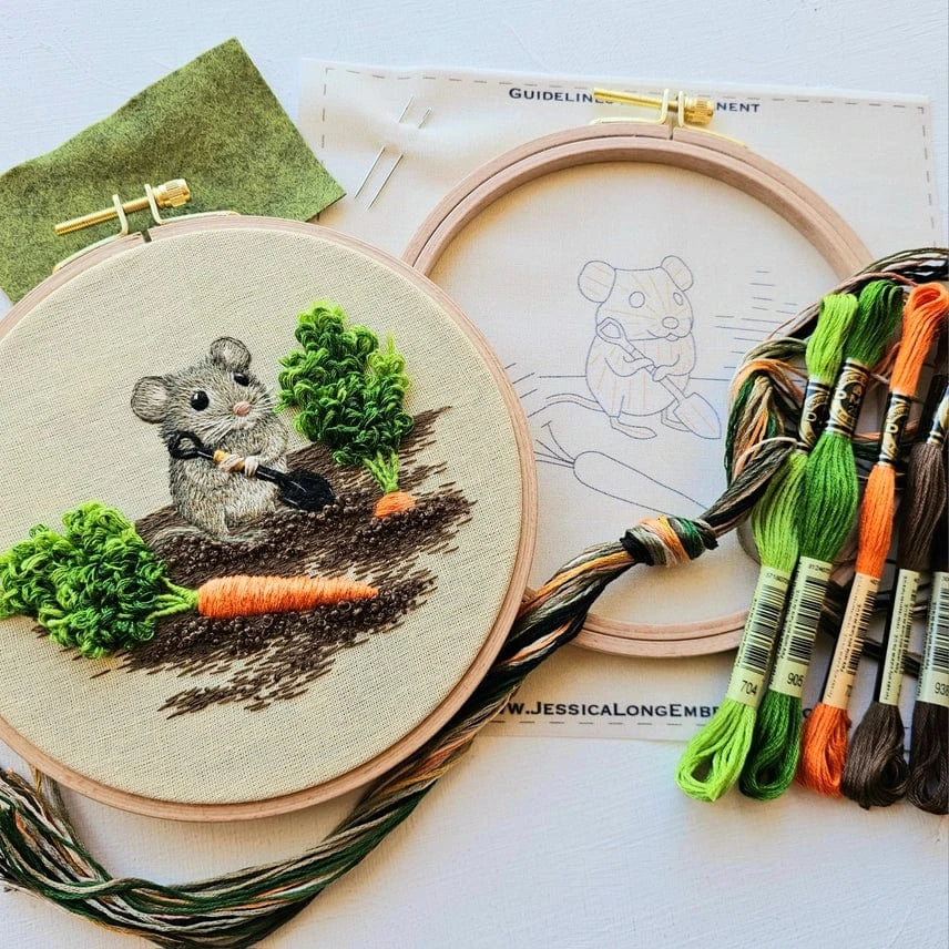 The 6 Garden Mouse Embroidery Kit by Jessica Long Embroidery includes a mouse and carrot outline on green fabric, colorful threads, and a hoop for thread painting your own stitched mouse holding a carrot among greenery.