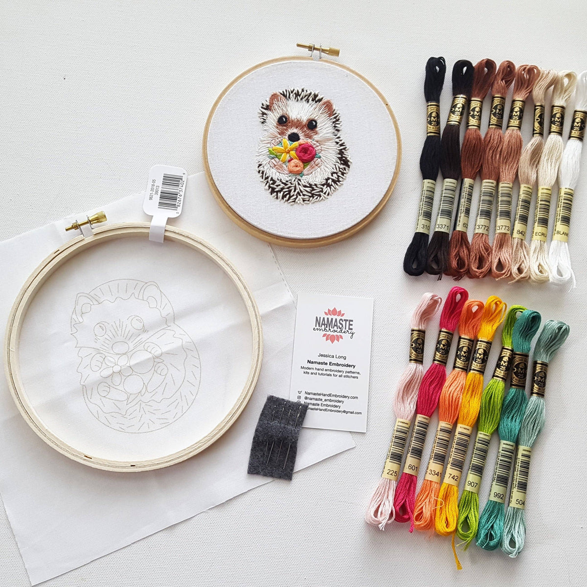 The 6 Hedgehog Embroidery Kit by Jessica Long Embroidery includes a finished hedgehog design, hoop art with fabric and outline, colorful floss skeins, a business card, and two felt pieces—all on a white surface.