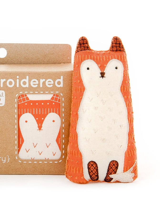 The Kiriki Press Beginner Fox Embroidery Doll Kit includes a small handmade fox plush with charming stitched details, sitting beside a matching screen-printed cardboard box.