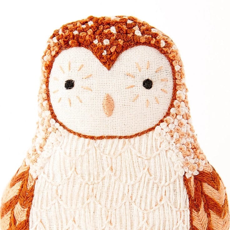Close-up of the Barn Owl Embroidery Doll Kit by Kiriki Press—a handmade plush with brown, white, and cream thread, featuring stitched eyes, beak, and feather details. Ideal for crafting enthusiasts or as an embroidery project.