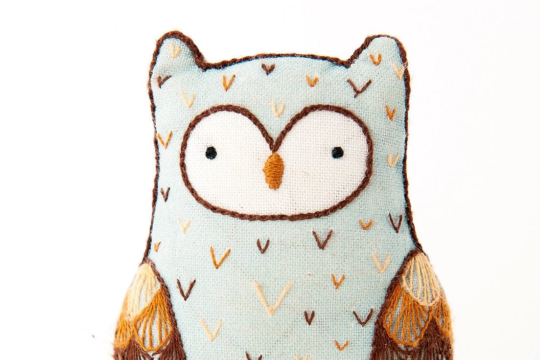 The Kiriki Press Beginner Horned Owl Embroidery Doll Kit features a handmade owl plushie with embroidered details and patterned wings—ideal for crafters seeking a charming DIY project.