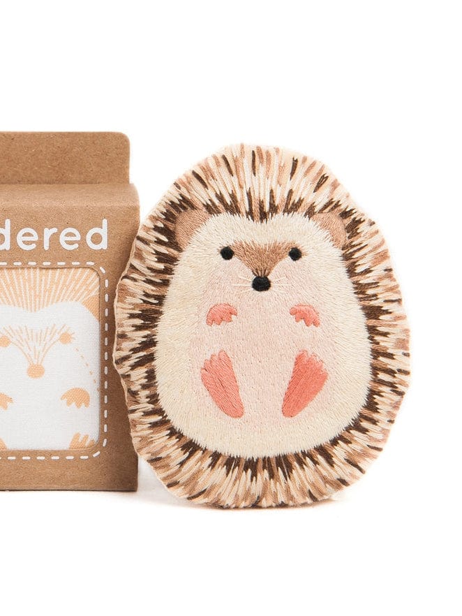 The Kiriki Press Hedgehog Embroidery Doll Kit features a plush hedgehog that stands upright, packaged in a box with a charming hedgehog illustration—ideal for embroidery enthusiasts and doll-making projects.