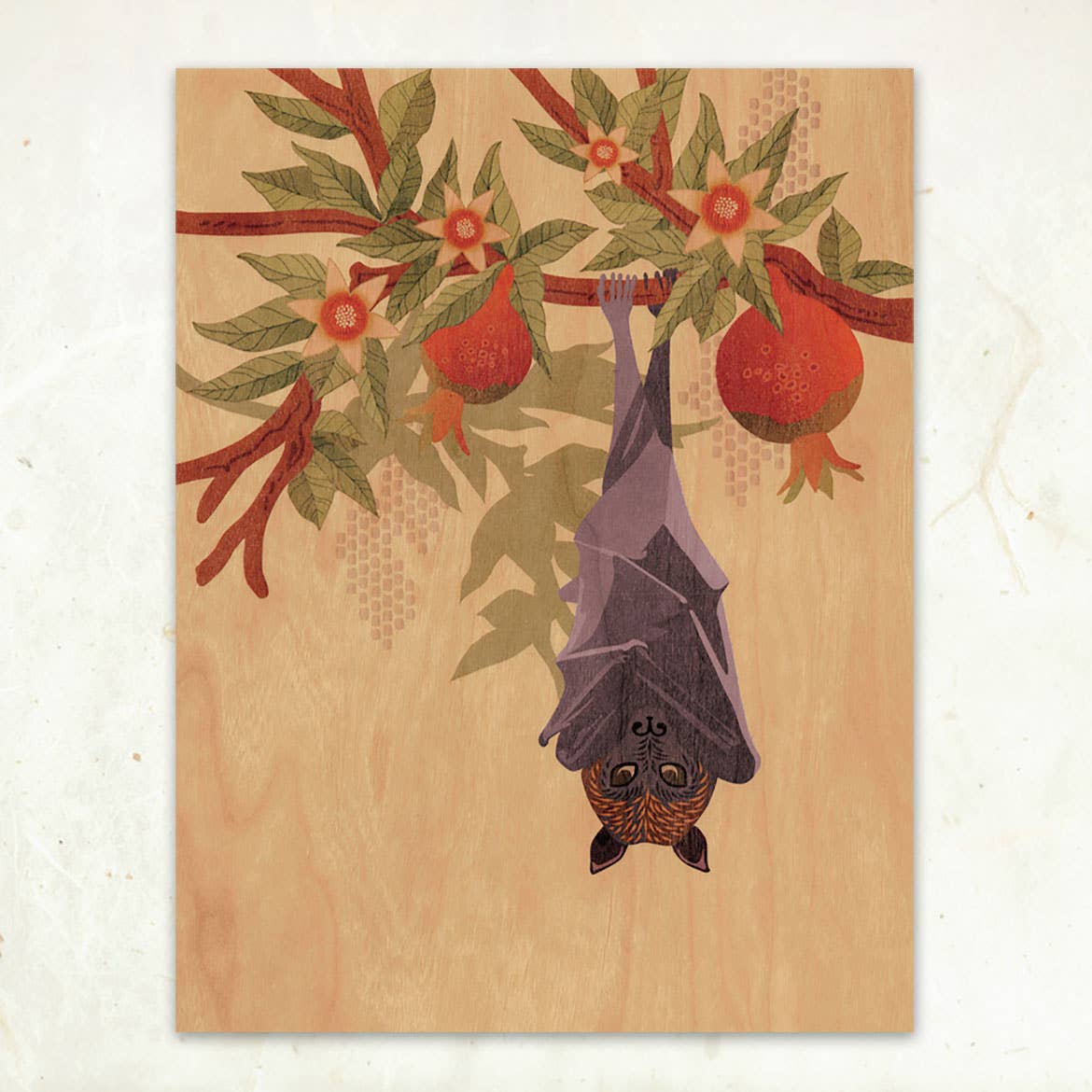 Fruit Bat and Pomegranate Small Wood Print by Little Gold Fox Designs features a bat hanging from a tree with green leaves and red pomegranates on a light wood-textured background, printed on sustainably-harvested wood veneer (11 x 8.5).