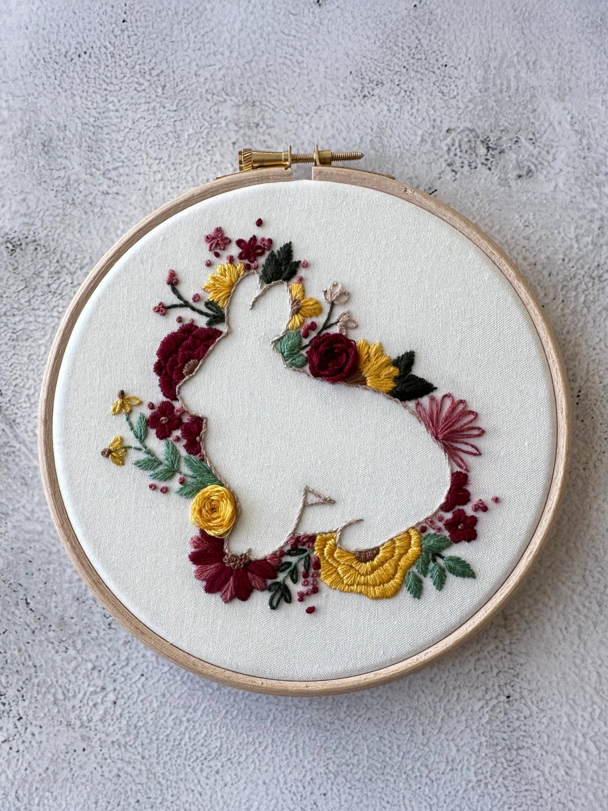 The Nest Embirdery 6 Beginner Spring Hops Embroidery Kit features a rabbit silhouette outlined with vibrant floral embroidery on white fabric—a delightful spring project ideal for beginners.
