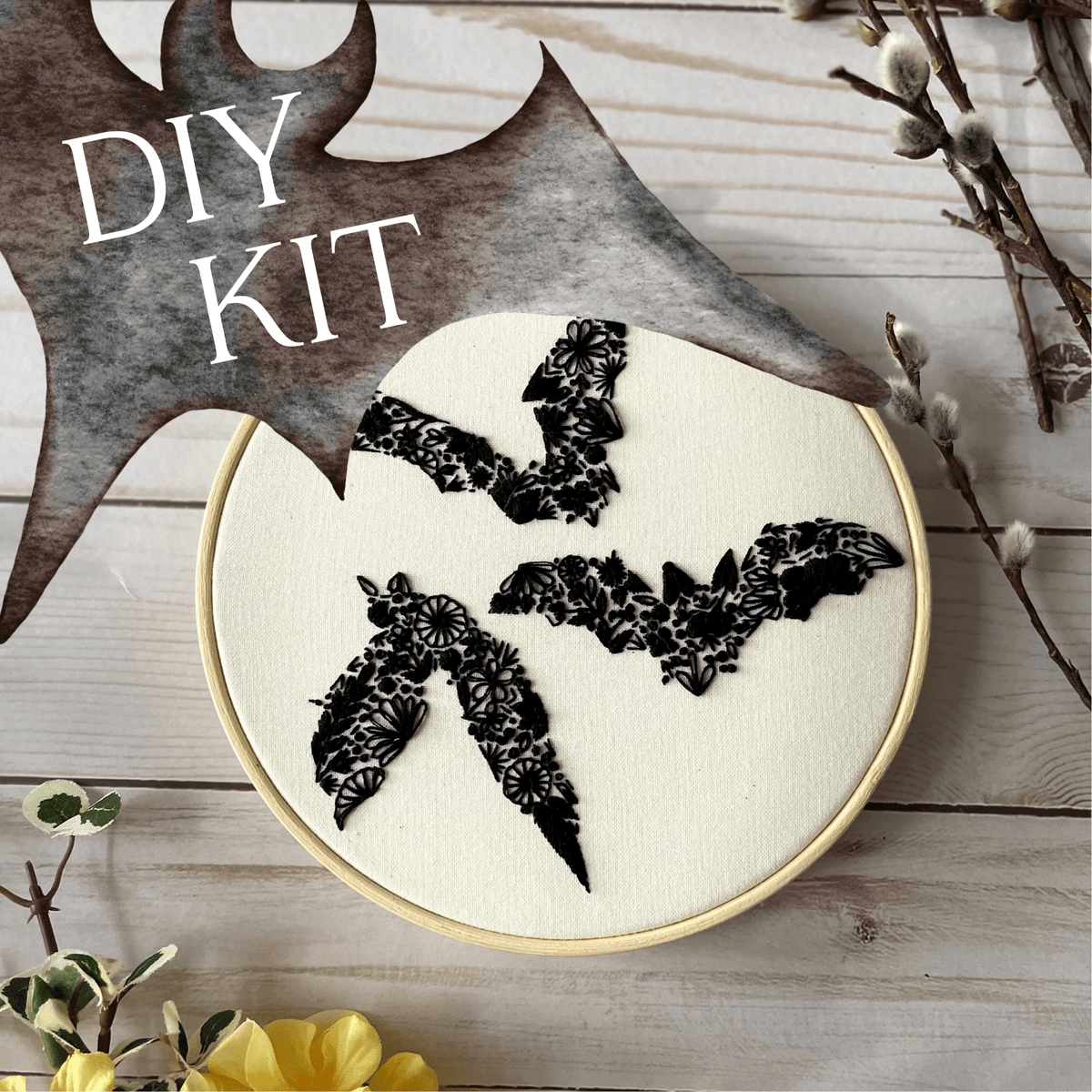 The *Late May Pre-Order* 6 Beginner Floral Bat Embroidery Kit by Nest Embirdery features three black, floral-patterned bats among spring flowers and pussy willow branches. DIY KIT appears on a textured background in the top left corner.