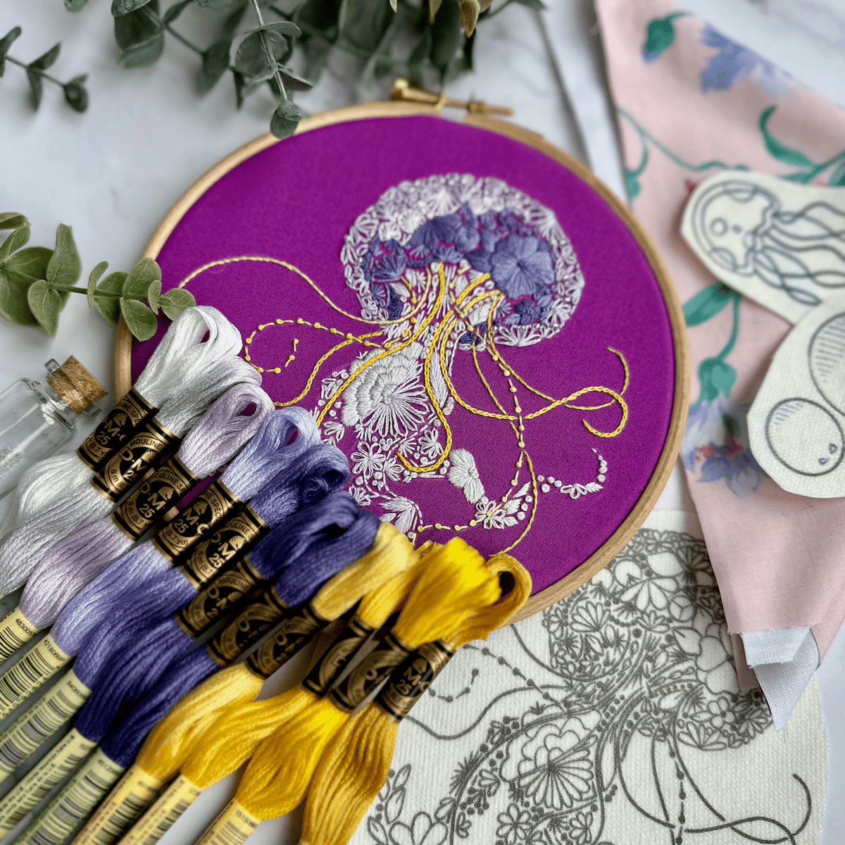 The Nest Embirdery 6 Beginner Jelly-Stitch Embroidery Kit features a detailed jellyfish design on purple fabric—ideal for anyone seeking a unique DIY or jellyfish embroidery kit.