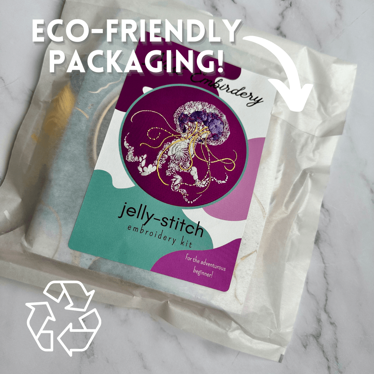 Nest Embirderys 6 Beginner Jelly-Stitch Embroidery Kit comes in eco-friendly packaging marked with a recycling symbol and the text ECO-FRIENDLY PACKAGING! plus an arrow, all set on a white marble background.