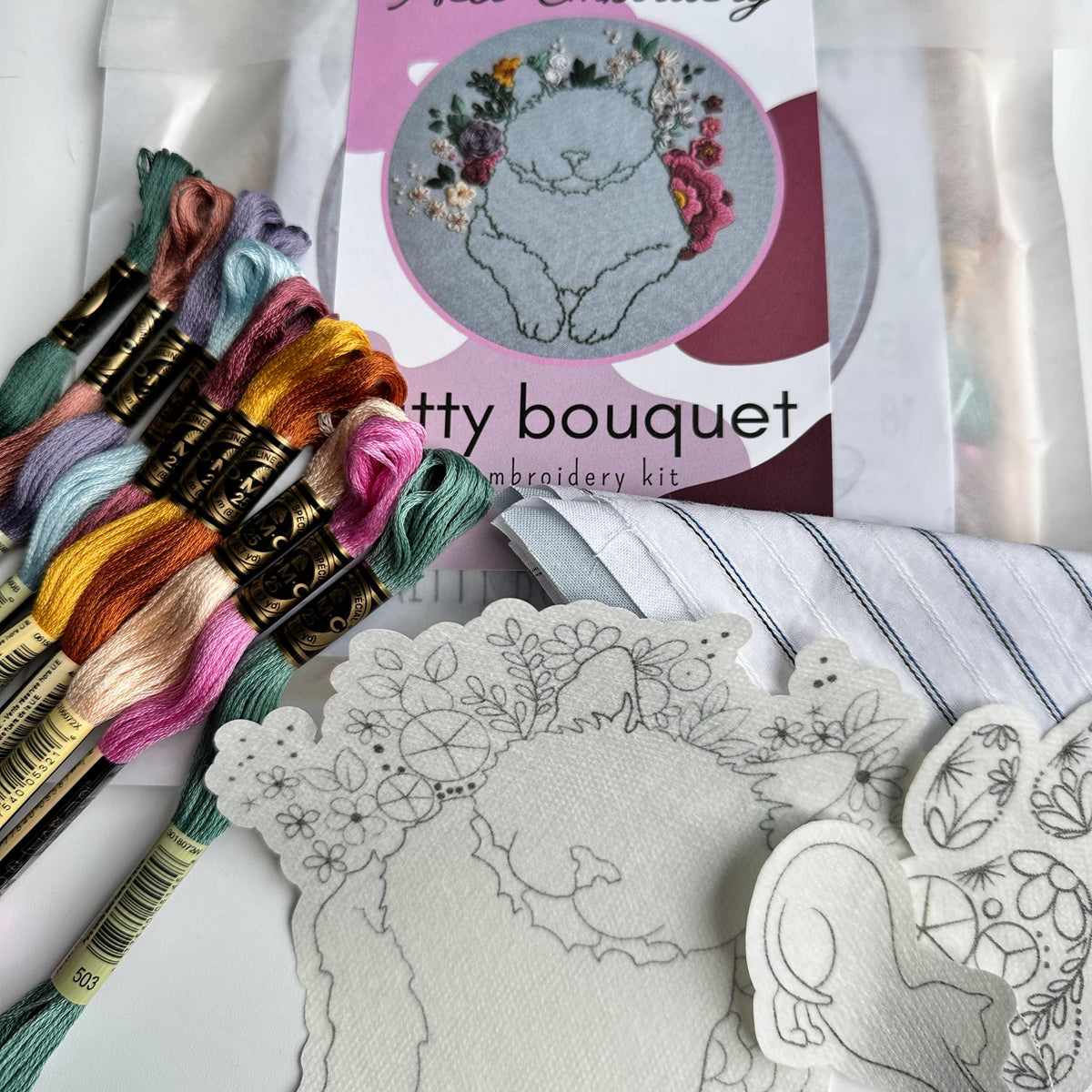 The 6 Beginner Kitty Bouquet Kit by Nest Embirdery is perfect for cat lovers and advanced beginners, offering pastel floss, patterned fabric, pre-printed floral cat and bunny designs, and a Kitty bouquet label.