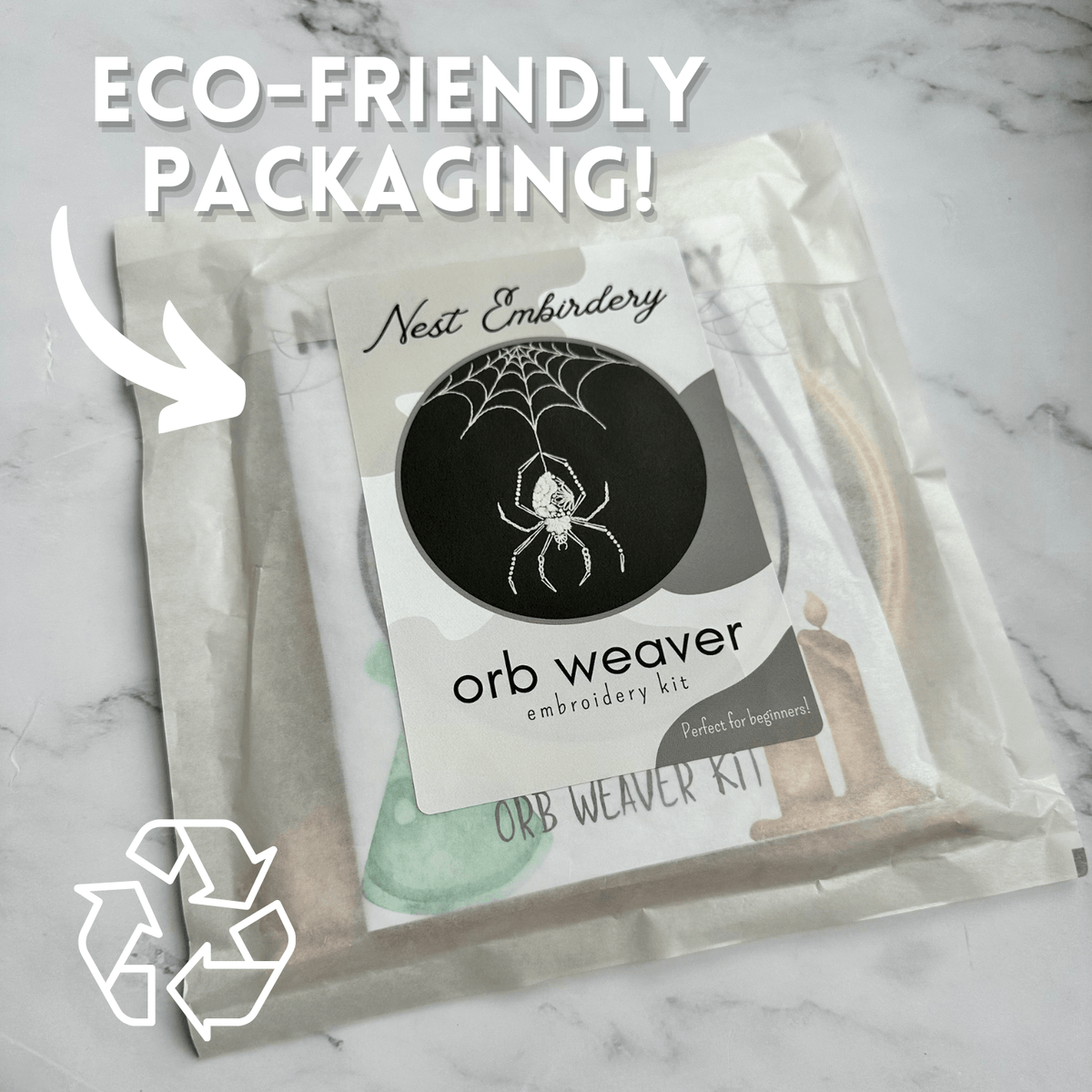 Nest Embirderys 6 Beginner Orb Weaver Spider Embroidery Kit comes in a translucent, eco-friendly bag labeled “ECO-FRIENDLY PACKAGING!” with a recycling symbol and an arrow highlighting the package.