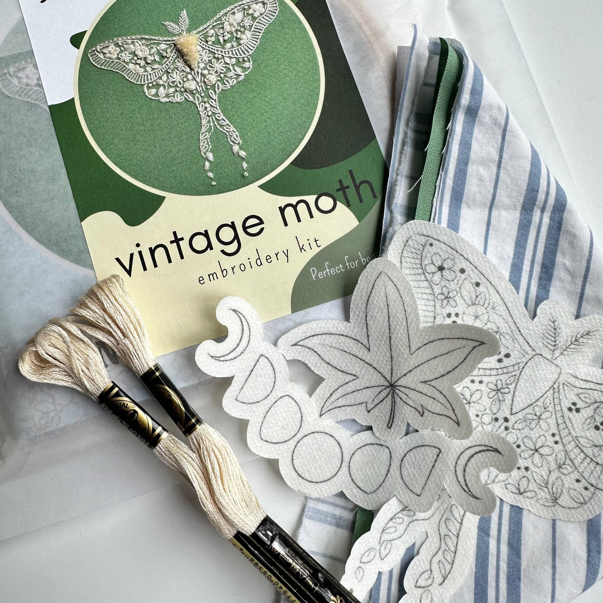 The *Late May pre-order* 6 Beginner Vintage Moth Embroidery Kit by Nest Embirdery includes a pattern booklet, embroidery floss, striped fabric, and cut-out moth and leaf designs—ideal for vintage craft beginners.