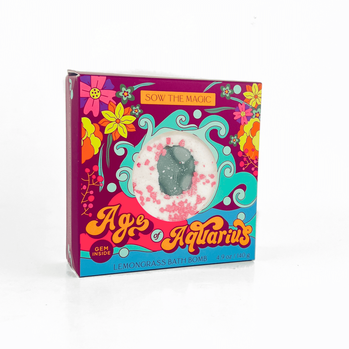 The Sow the Magic Age of Aquarius Lemongrass Bath Bomb features an Aventurine stone inside, packaged in a colorful box with floral and swirl designs and Sow the Magic on top for spiritual healing vibes.