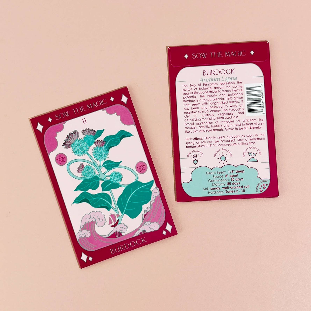 Two red Burdock Tarot Garden Seed Packets by Sow the Magic feature illustrated burdock plants and growing instructions. Prized as a medicinal herb and detoxifying vegetable, the packets are set against a pale pink background.