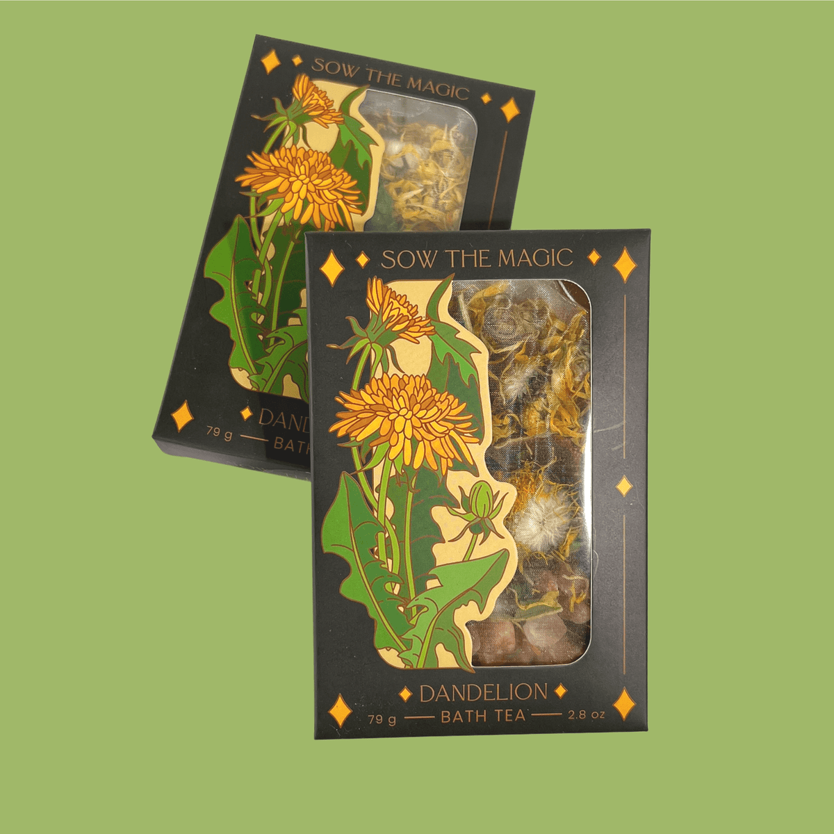 Two black boxes of Sow the Magic Dandelion Tarot Botanical Bath Tea, featuring yellow dandelion art and clear windows showing detoxifying herbs, are displayed on a light green background—perfect for a soothing herbal soak.