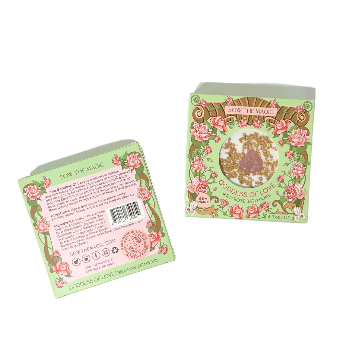 Two decorative green and pink boxed Sow the Magic Goddess of Love Wild Rose Bath Bomb with Rose Quartz are shown. One has a rose design and bath bomb window; the other highlights its rose scent and Epsom salt for self-care.