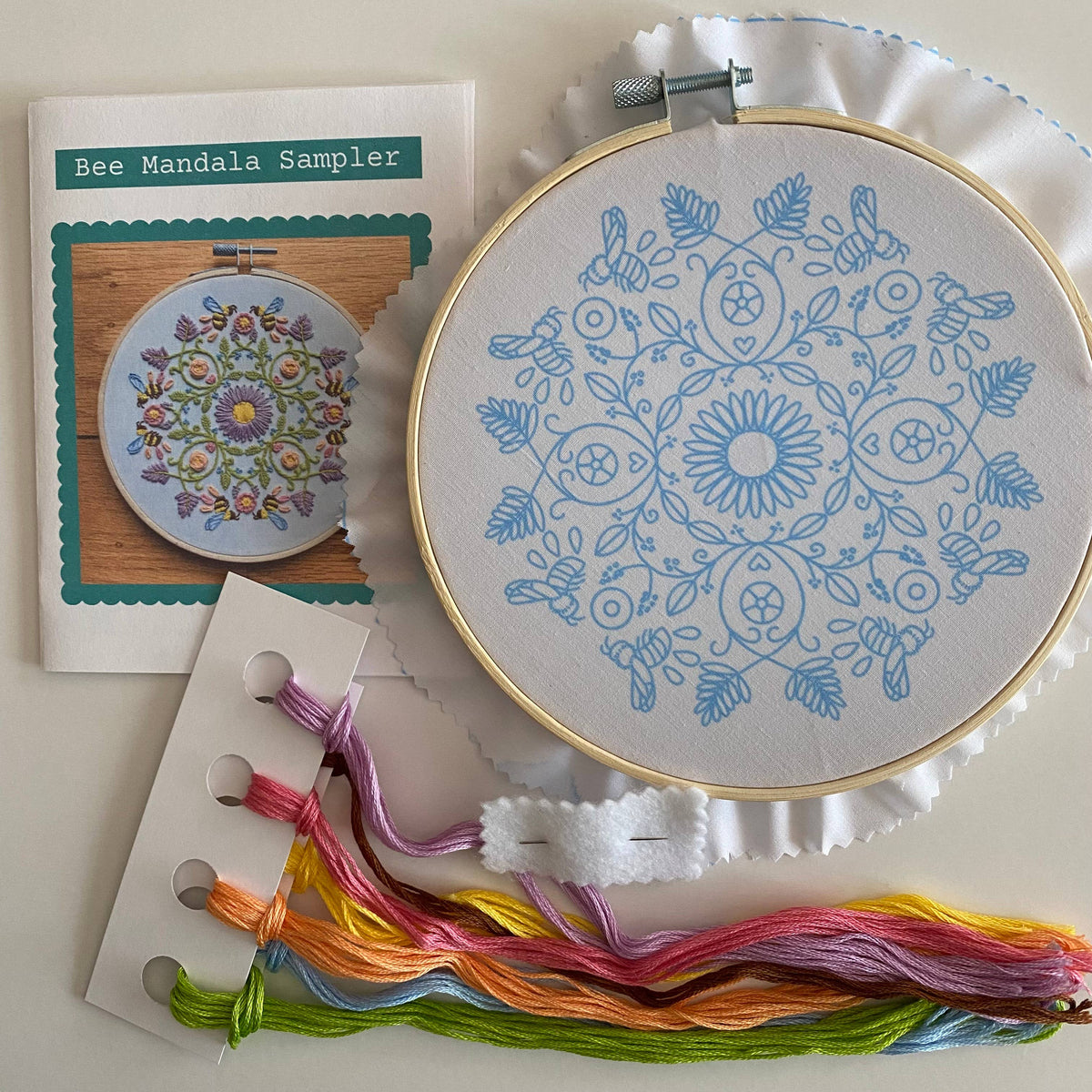 The Stitches By Tiff 6 Bee Mandala DIY Embroidery Kit includes a pre-printed fabric in hoop, colorful floss, floss holder, and instruction booklet—perfect for beginner embroidery art projects.