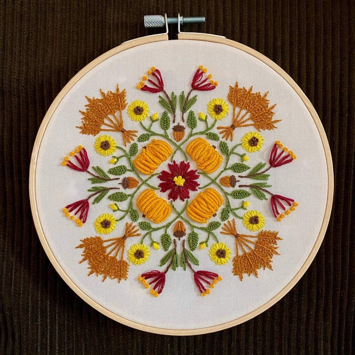 The 6 Harvest Mandala DIY Embroidery Kit by Stitches By Tiff features a symmetrical autumn design with pumpkins, flowers, and orange leaves on white fabric—ideal for creative crafts or DIY art projects.