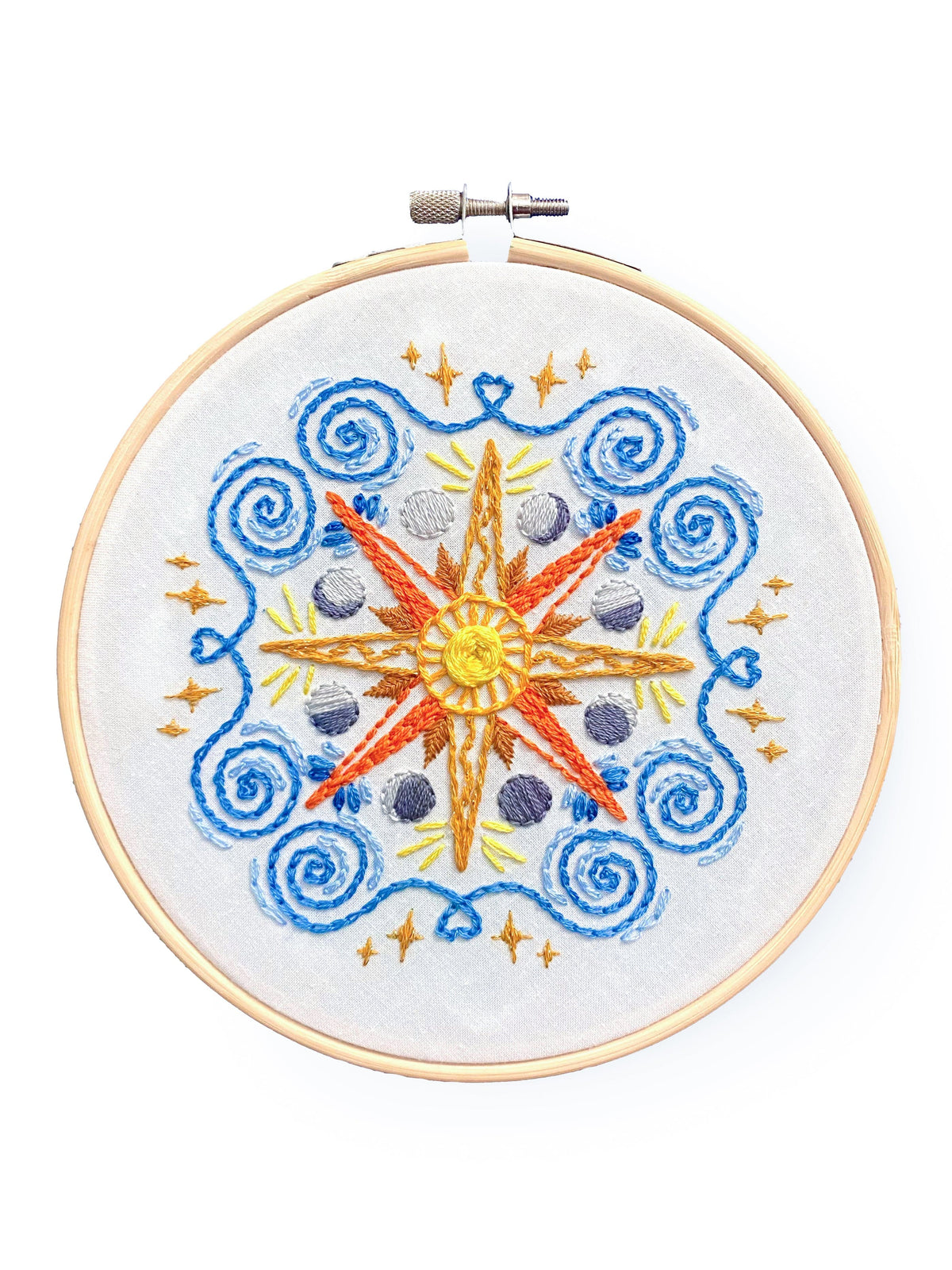 The 6 Beginner Celestial Mandala Sampler Embroidery Kit by Stitches By Tiff features a vibrant sun, compass rose, moons, stars, and blue swirls on white fabric—ideal for beginners or creative DIY projects.