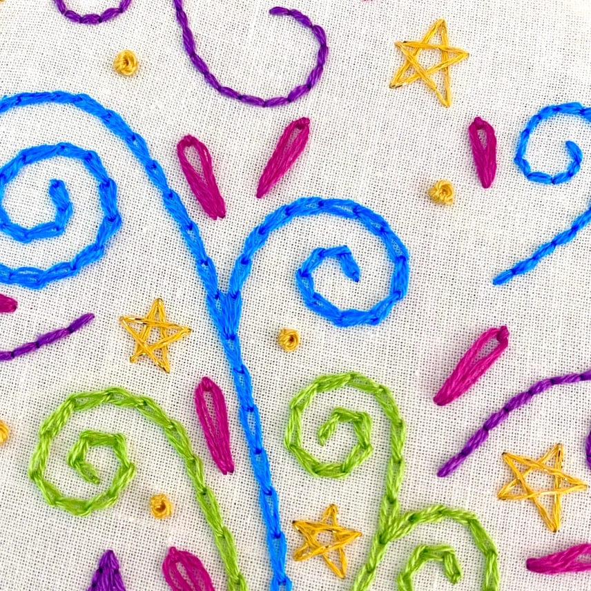 The 6 Beginner The Meowgician Embroidery Kit by Stitches By Tiff features colorful embroidery on white fabric with blue and green swirls, yellow stars, dots, and magenta petals in a lively, whimsical pattern—perfect for beginners.