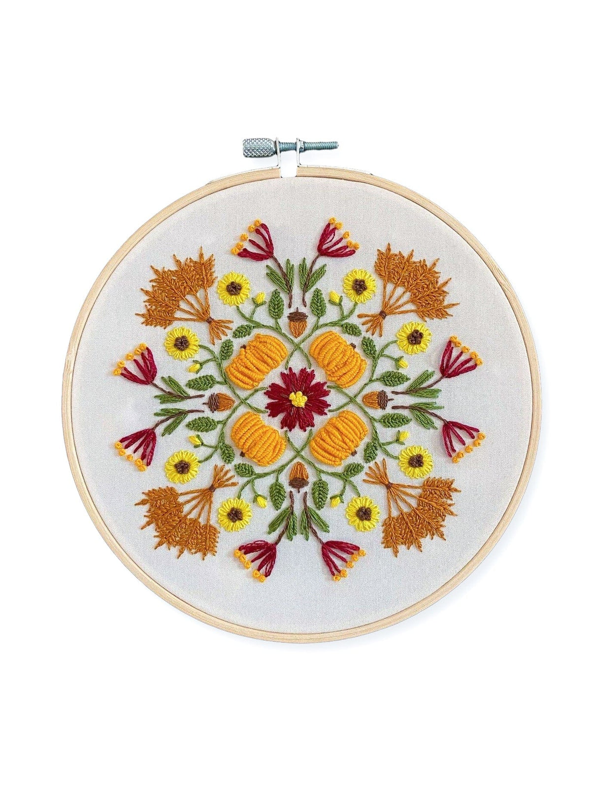 The Stitches By Tiff 6 Harvest Mandala DIY Embroidery Kit features a round hoop with a symmetrical floral design in autumn-inspired orange, yellow, red, and green threads on white fabric—ideal for creative crafts and art projects.