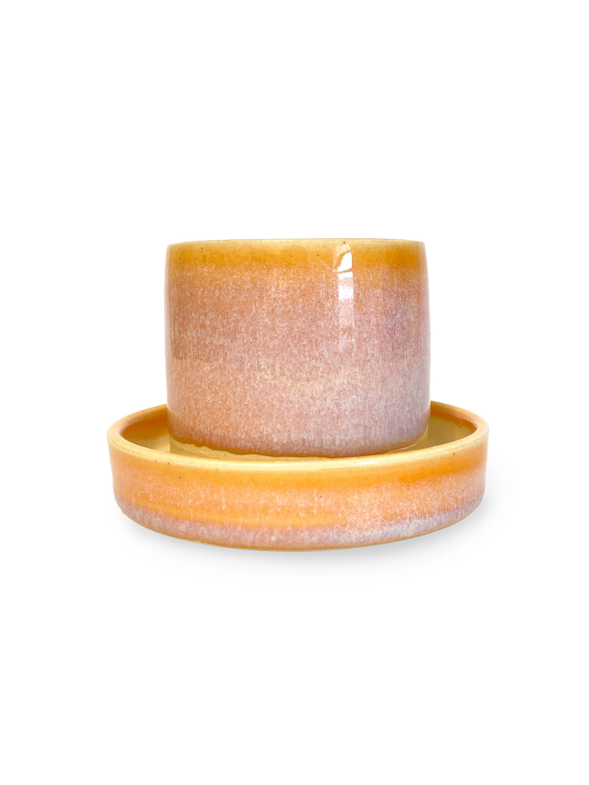The 2.5 Small Ceramic Sunrise Planter by Swan City Ceramics is handmade from white stoneware with a matching saucer and showcases a sunrise-inspired gradient glaze in warm yellow, orange, and light purple on white.