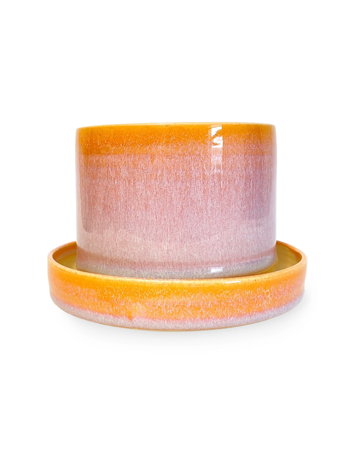 The Swan City Ceramics 4 Ceramic Sunrise Planter with matching saucer features a glossy gradient of yellow, pink, and lavender on white stoneware, displayed on a white background.