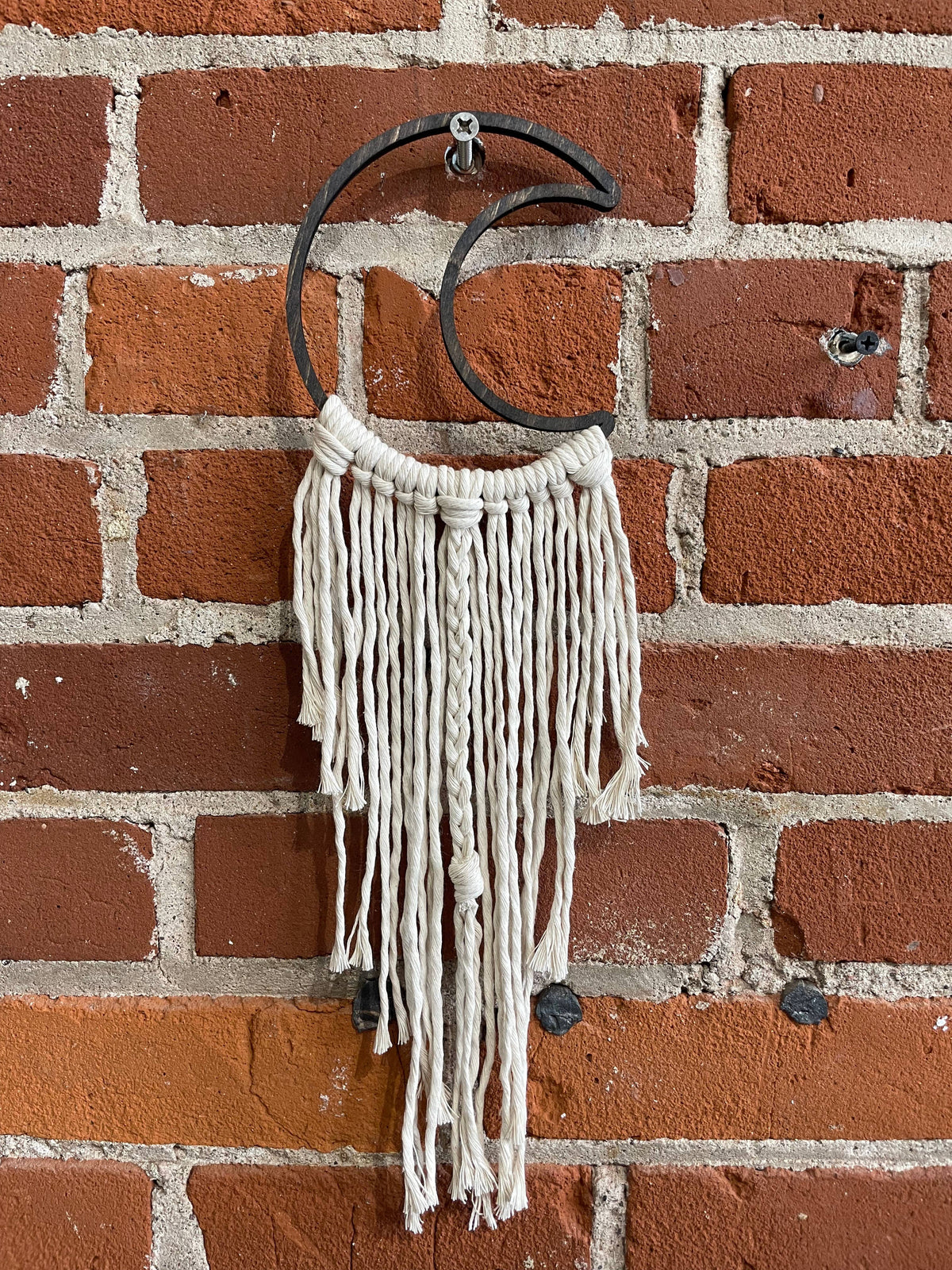 The DIY Open Moon Beginner Mini Macrame Kit by Tangled Up In Hue features a crescent metal ring with white cords and braids, creating a stylish wall hanging ideal for unique macrame projects.