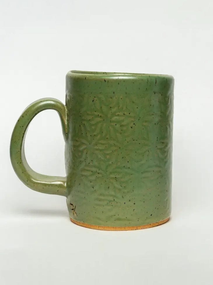 The Mushroom Design Handmade Ceramic Mug by White Squirrel Clayworks is a 16oz green, handmade stoneware mug with a textured leaf pattern, speckled surface, curved handle, and an unglazed rim, shown on a plain white background.